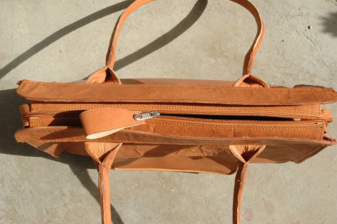 Tan leather shoulder bag with structured rectangular shape and dual handles, flat lay view on neutral background