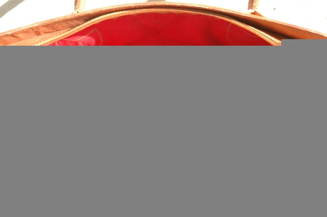 Red leather bag with curved top handle and tan trim detail, front view
