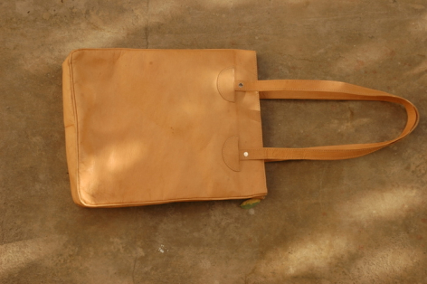 Tan leather shoulder bag with flat rectangular body and two parallel handles, displayed flat against neutral background