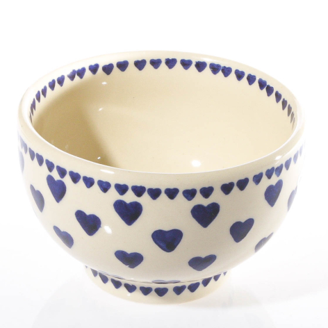 Cream ceramic bowl with blue heart pattern border, front view showing interior depth