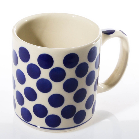 Cream ceramic mug with cobalt blue polka dot pattern, front view showing handle and cylindrical shape