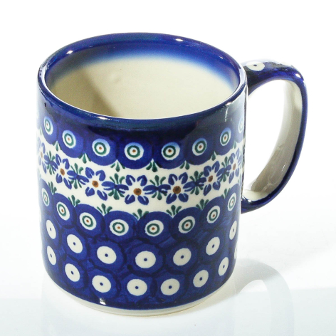 Navy ceramic mug with white floral dot pattern all over, filled with cream-colored liquid, front three-quarter view