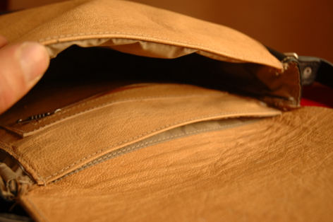 Tan leather bag open to show dark interior lining and metal clasp detail