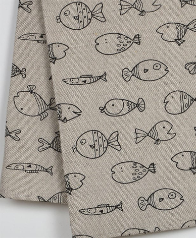 Beige linen textile with hand-drawn fish and starfish pattern in dark ink, folded to show print detail