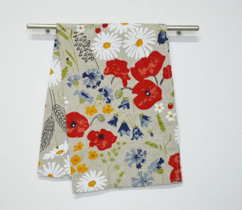 Red and blue floral patterned textile hanging from metal rod, showing vibrant botanical print on cream background