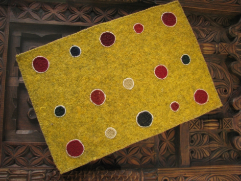 Bright yellow textile with multicolored polka dots in red, navy, and cream, angled display