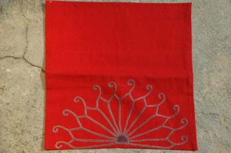 Red leather clutch with embossed radiating line design, front flap open showing interior