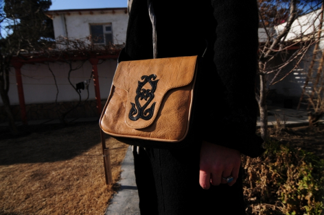 Hellbraune Ledertasche mit geometrischem Muster, seitliche Ansicht, von Person getragen