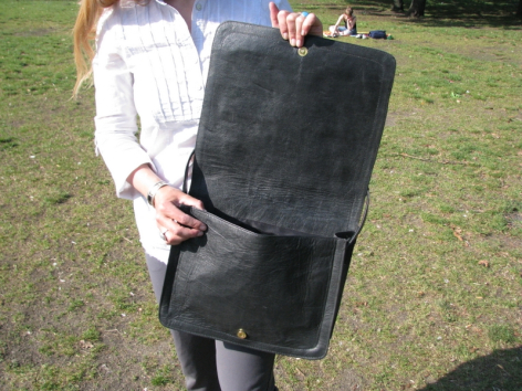 Person hält schwarze Ledertasche mit Klappendeckel, Vorderansicht, handwerklich verarbeitet