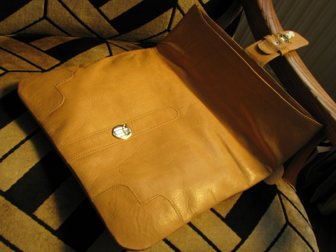 Gelbe Ledertasche aus Leder mit glänzender Oberfläche und silbernem Verschluss, von oben fotografiert
