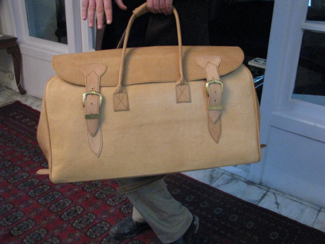 Hellbraune Ledertasche mit Henkeln, Frontalansicht, auf strukturiertem Untergrund platziert