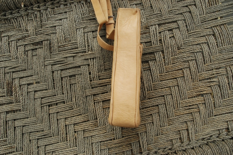 Holzgriff aus hellem Holz auf strukturiertem grauem Weben, Detailaufnahme des Handgriffs einer Handwerkstasche