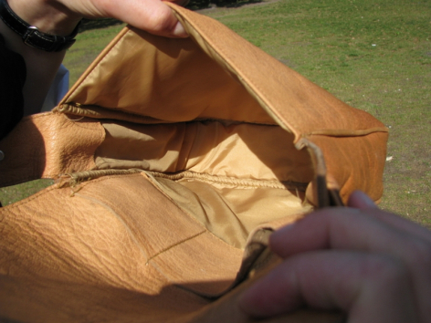 Handwerkerin faltet braune Ledertasche während der Herstellung, Detailaufnahme der Handarbeit