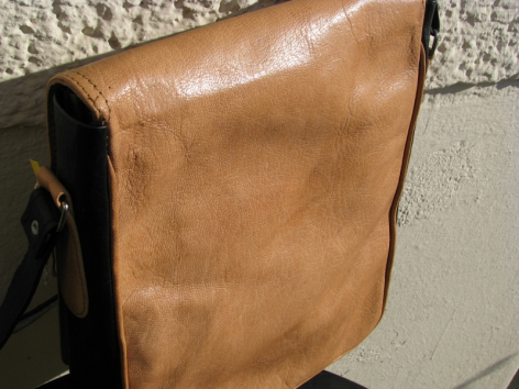 Cognacbraune Ledertasche von vorne, rechteckige Form mit schwarzem Schultergurt, handwerklich gefertigt