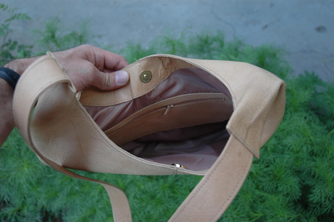 Braune Ledergeldbörse in beiger Stofftasche, von Hand gehalten, Innenansicht mit offener Klappe