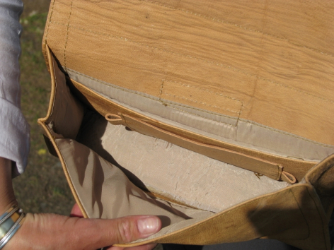 Brown leather bag open showing cream canvas lining and interior pocket detail