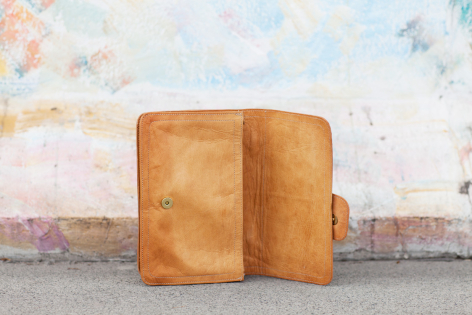 Tan leather crossbody bag with flap closure, front view showing worn patina and structured rectangular shape