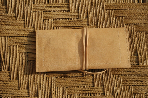 Deux sacs en cuir beige de forme carrée posés sur un tapis tissé à motifs géométriques