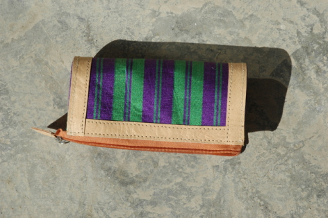 Tan leather wallet with open compartments displaying colorful striped textile insert in purple, green, and black tones