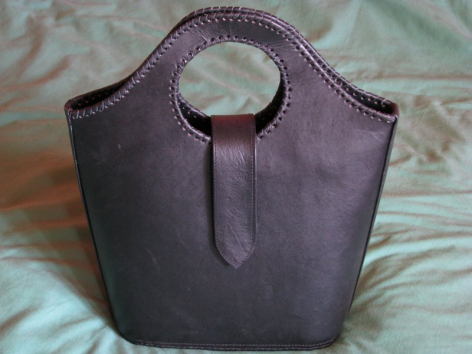 Dunkelviolette Ledertasche mit trapezförmiger Form und rundem Henkel, Vorderansicht