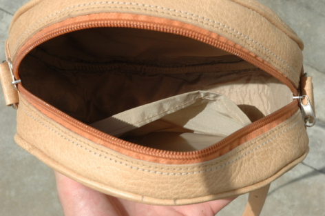 Hellbraune Leder-Handtasche, oben offen, mit Innenfutter und hellen Textilien sichtbar, in Handansicht von vorne