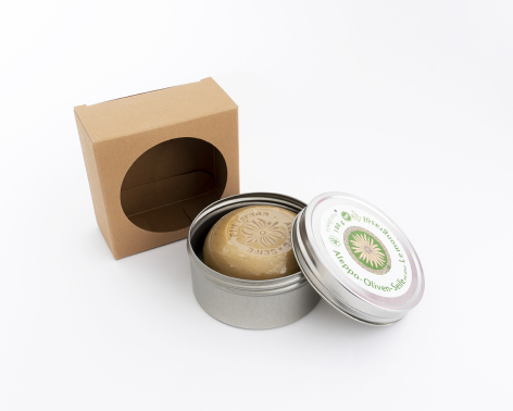 Metallic silver jar with white lid containing beige powder, displayed open next to kraft paper box on white background