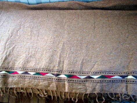 Beige linen textile with colorful striped border trim and frayed edge, flat lay view
