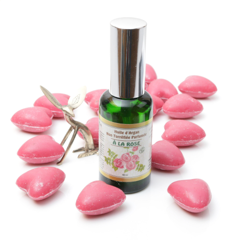 Green glass bottle with silver atomizer top surrounded by pink decorative petals and white flowers