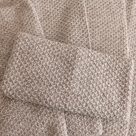 Beige woven textile with geometric diamond pattern, folded to show texture and weave detail