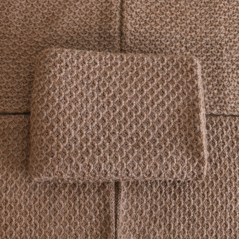 Beige wool textile with geometric woven pattern, folded flat lay view showing fabric texture and natural fiber weave