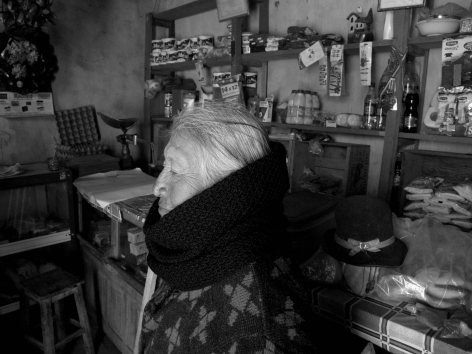 Artisan working at wooden loom with threads, weaving textile by hand in workshop setting, black and white photograph