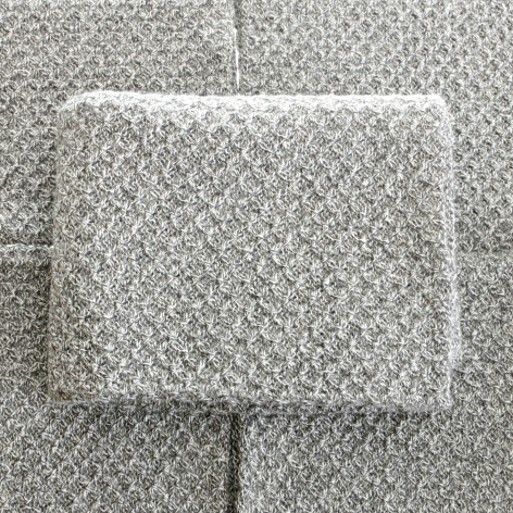 Cream textured pouch with geometric jacquard weave pattern, displayed flat on matching woven fabric background