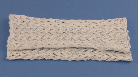 Beige textile headband with textured woven pattern, front view against blue background