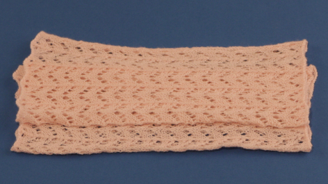 Woven rectangular textile in natural tan with textured surface pattern, laid flat against blue background