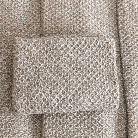 Beige Textil mit strukturiertem Muster in Nahaufnahme, handwerklich gewebtes Material mit Faltenwurf