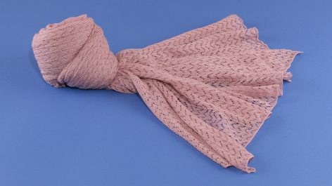 Dusty pink pleated textile wrap with gathered ends, displayed against blue background