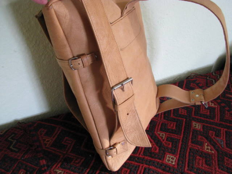 Tan leather tote bag with structured handles, displayed open to show interior capacity and craftsmanship detail