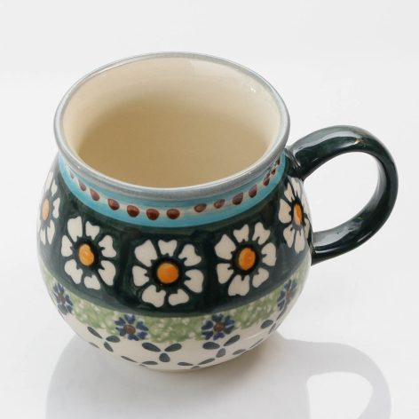 Dark ceramic mug with white and yellow floral pattern and decorative dots, front view with black handle