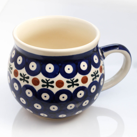 Deep blue ceramic mug with white polka dots and colorful flowers, rounded bulbous shape, cream interior