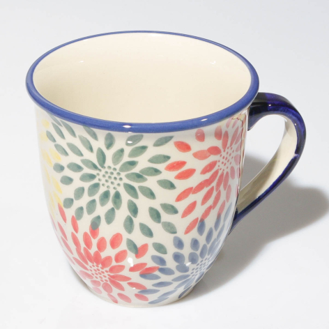 Cream ceramic mug with colorful radial floral pattern and blue rim, front view