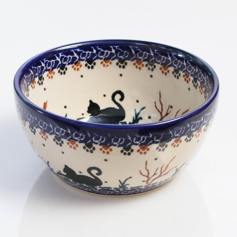 Deep blue and cream ceramic bowl with hand-painted silhouettes of birds and floral motifs, shown from above at an angle