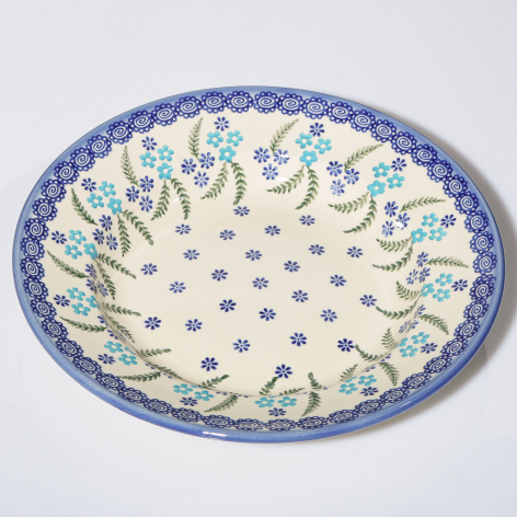 Blue and cream ceramic bowl with floral border pattern and dotted center, overhead view