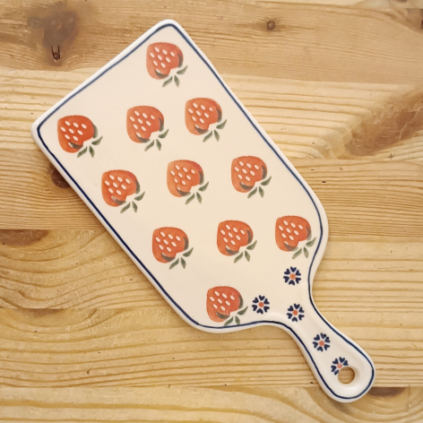 Ceramic serving paddle with coral rose pattern on white glaze, displayed flat on wooden surface