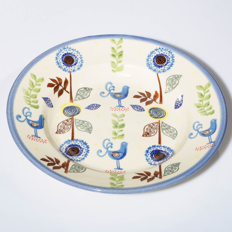 Cream ceramic plate with blue rim featuring hand-painted floral and botanical motifs in blue, yellow, and red tones