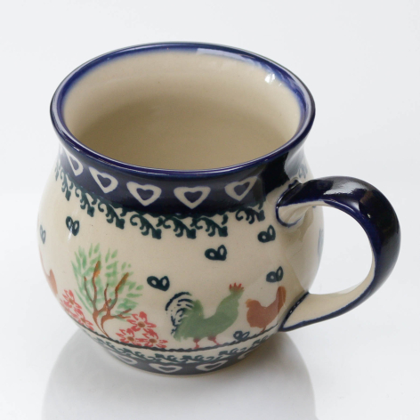 Cream ceramic mug with blue rim and handle, decorated with navy floral pattern and hand-painted botanical illustration