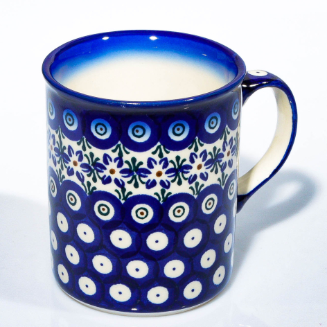 Blue ceramic pitcher with white geometric and floral patterns, front view showing decorative details and handle