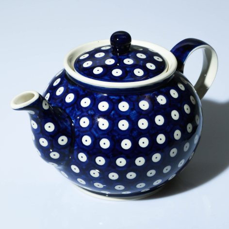 Navy blue ceramic teapot with white polka dot pattern, rounded body, domed lid with finial, and curved spout, front view