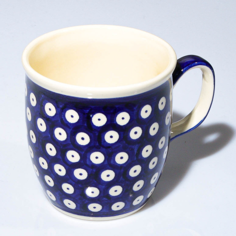 Navy ceramic mug with white polka dot pattern and cream interior, front three-quarter view