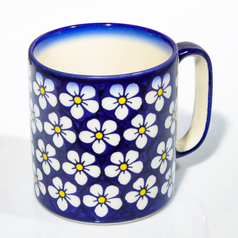 Deep blue ceramic mug with white and yellow daisy flower pattern covering the surface, front view