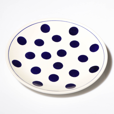 White ceramic bowl with navy blue polka dots, viewed from above at slight angle